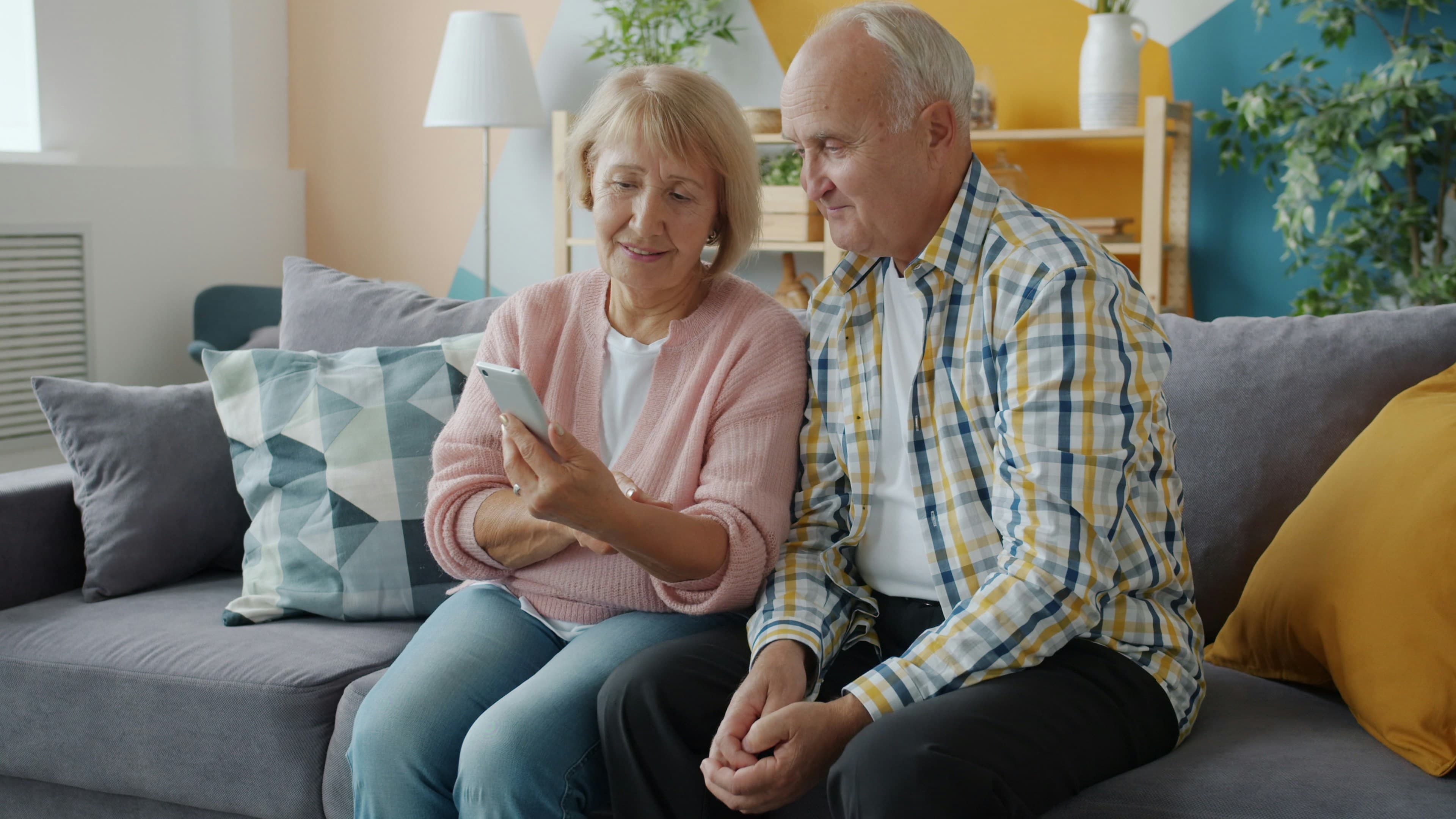 Elderly couple on couch looking at smartphone together