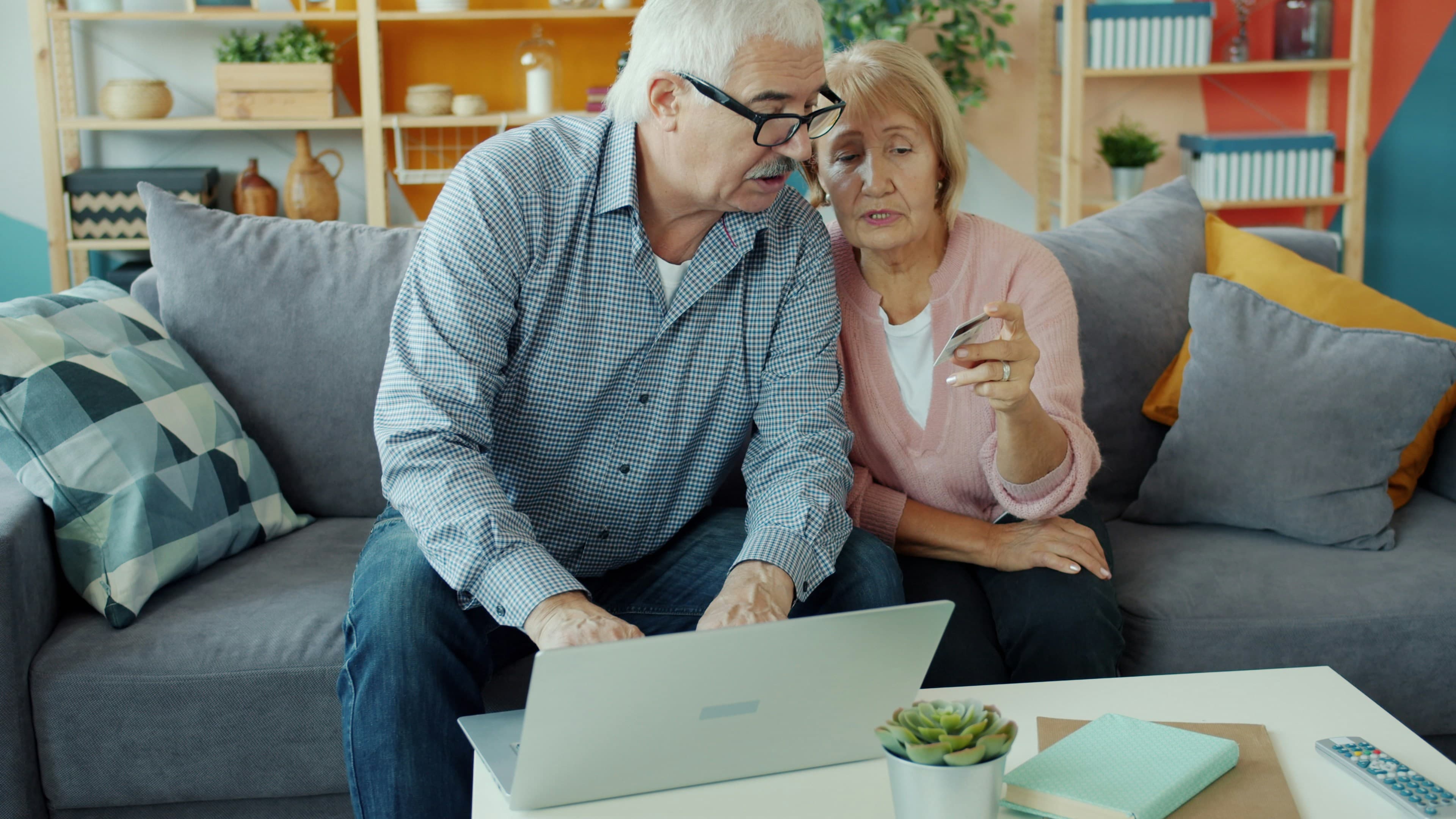 Elderly couple learning together on laptop with credit card