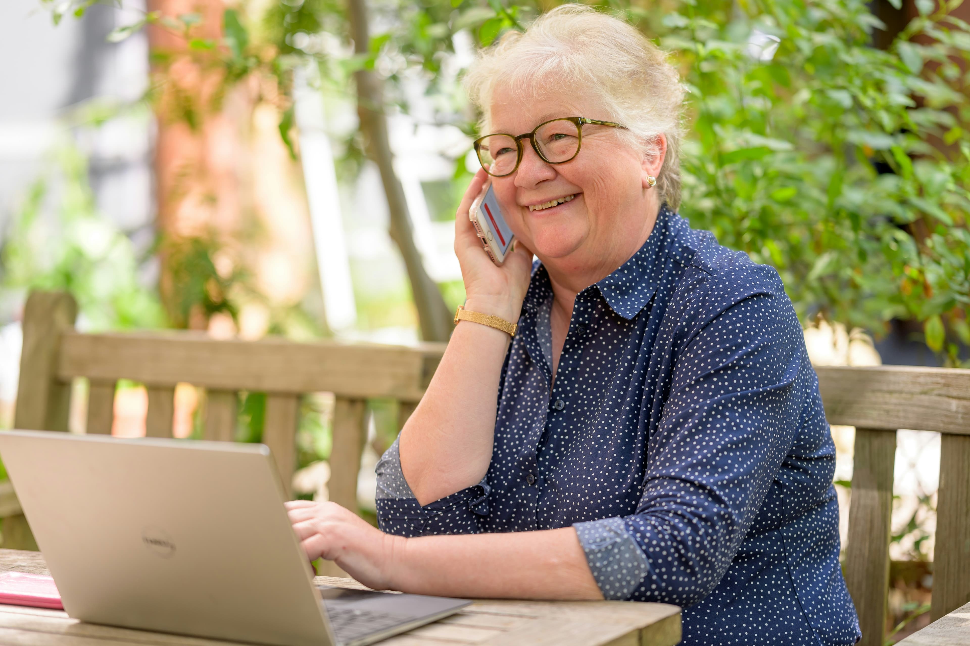 Smiling elderly person learning on phone during computer lesson