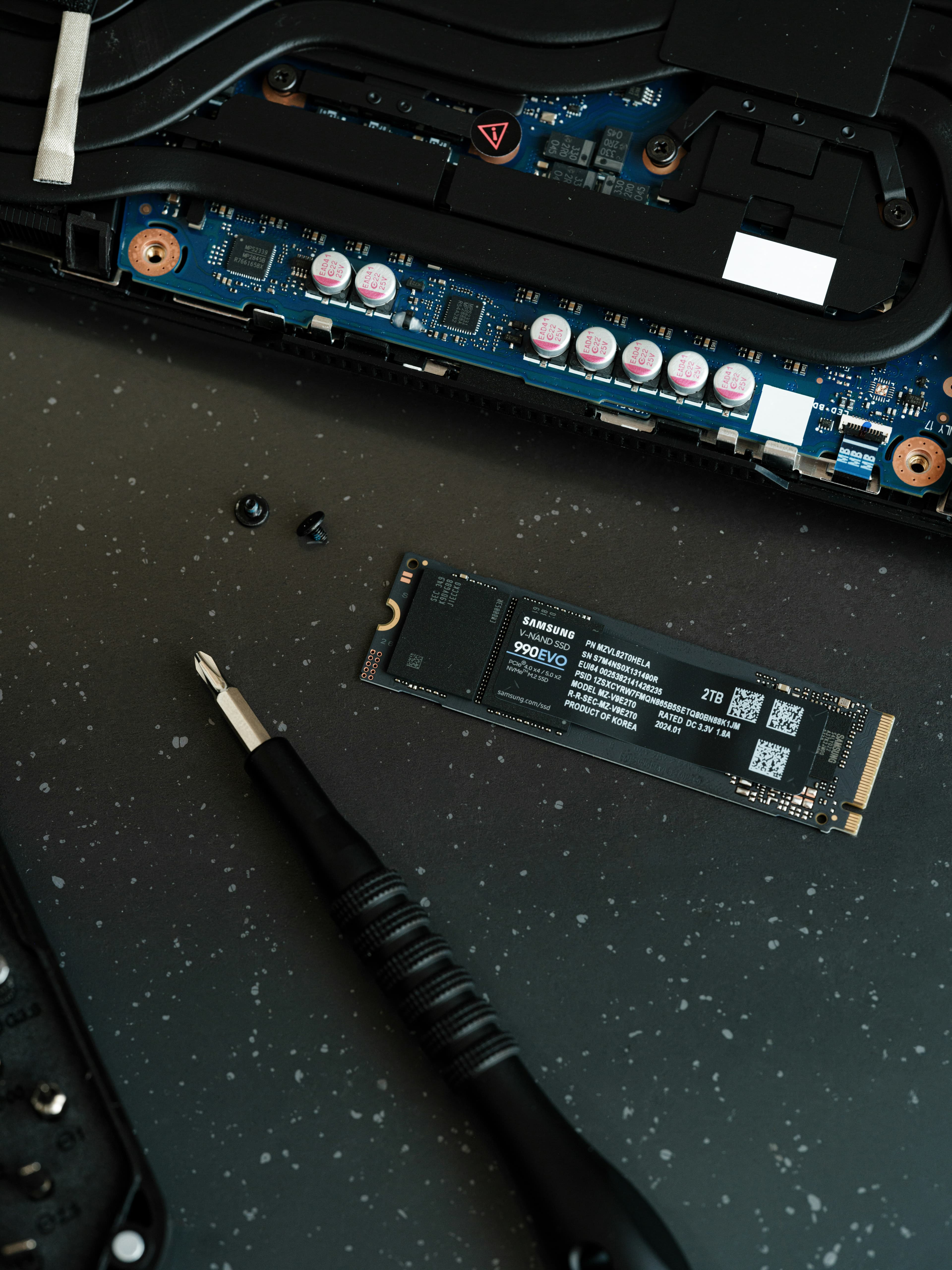 Samsung M.2 SSD next to screwdriver and opened laptop